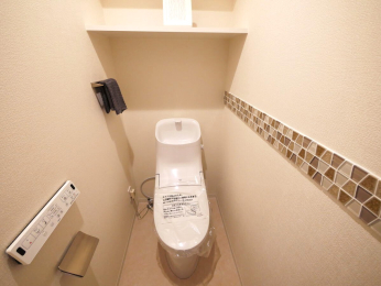 　温水洗浄機能付きトイレ。アクセントタイルがワンポイントとなったオシャレな空間。